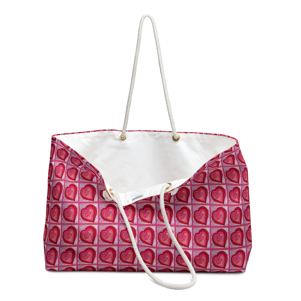 A tote bag with a pink and red heart pattern on the exterior, a white interior lining, and white rope handles, shown against a plain white background.