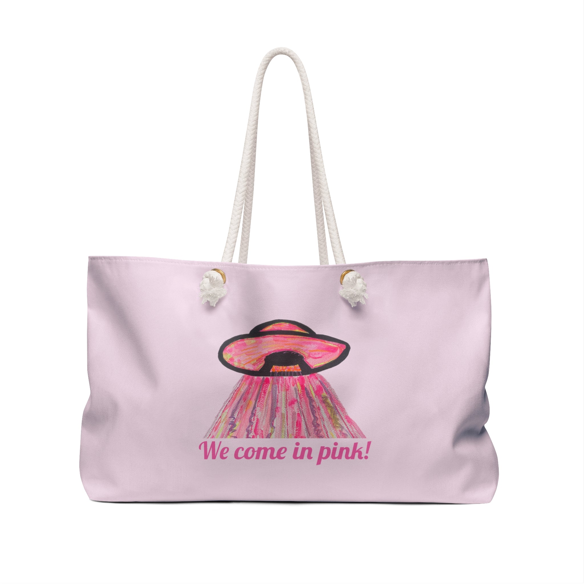A light novelty pink tote bag with white rope handles, featuring a graphic of a pink and black UFO with the text 'We come in pink!' printed on the front.